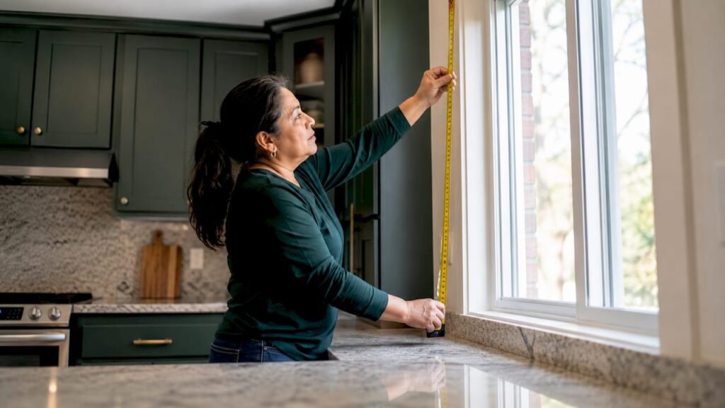 Homeowner measuring window opening indoors